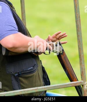 Un homme charge un fusil de chasse avec deux cartouches à un tir au pigeon d'argile. Banque D'Images