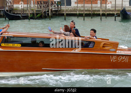 Les touristes asiatiques bénéficiant de la balade dans un taxi d'eau le long du Grand Canal, Venise, Italie Banque D'Images