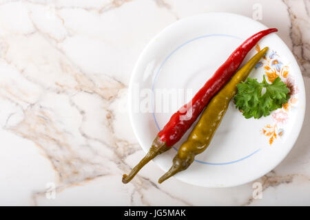 Vert et Rouge marinés poivre pepperoni dans la plaque sur la table de persil Banque D'Images