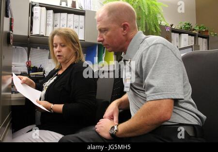 Kenneth Edwards, droite, regarde au-dessus de la paperasse financière avec Joanna Mayer dans la direction de contrôleur au cours de la 5ème journée annuelle protégé au Marine Corps Air Station Cherry Point, N.C., 21 juin 2017. Jour protégé a été créé en 2012 afin de permettre aux personnes handicapées de la communauté locale l'occasion de participer à l'observation au poste de travail, avec la possibilité d'être engagé. Mayer est un technicien au MCAS Cherry Point. (U.S. Marine Corps photo par Lance Cpl. Justin Roux/ libéré) Banque D'Images