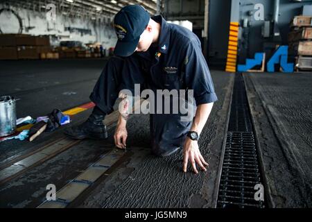 170624-N-QN175-110 OCÉAN ATLANTIQUE (24 juin 2017) 3ème classe 4400 Machiniste Nicholas Caudil corrosion effectue des opérations de maintenance sur un pont rail de porte dans la zone du porte-avions USS Dwight D. Eisenhower (CVN 69)(IKE). Ike est en cours pendant la phase de maintien en puissance de la flotte (Plan d'intervention optimisés OFRP). (U.S. Photo par marine Spécialiste de la communication de masse 3 Classe Dartez C. Williams) Banque D'Images