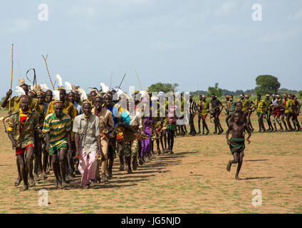 Les hommes d'exécution en ligne avec armes pendant la cérémonie à l'ox fière tribu Dassanech, comté de Turkana, Omorate, Ethiopie Banque D'Images