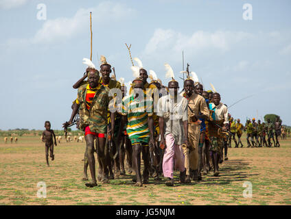 Les hommes d'exécution en ligne avec armes pendant la cérémonie à l'ox fière tribu Dassanech, comté de Turkana, Omorate, Ethiopie Banque D'Images