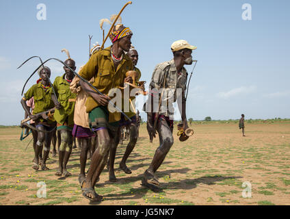 Les hommes d'exécution en ligne avec armes pendant la cérémonie à l'ox fière tribu Dassanech, comté de Turkana, Omorate, Ethiopie Banque D'Images