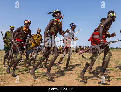 Les hommes d'exécution en ligne avec armes pendant la cérémonie à l'ox fière tribu Dassanech, comté de Turkana, Omorate, Ethiopie Banque D'Images