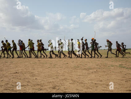 Les hommes d'exécution en ligne avec armes pendant la cérémonie à l'ox fière tribu Dassanech, comté de Turkana, Omorate, Ethiopie Banque D'Images