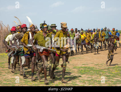 Les hommes d'exécution en ligne avec armes pendant la cérémonie à l'ox fière tribu Dassanech, comté de Turkana, Omorate, Ethiopie Banque D'Images