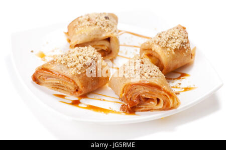 Crêpes roulées avec mousse au caramel et noix. On white Banque D'Images