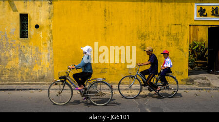 Une Vietnamienne monte un vélo dans une rue de Hoi An, Vietnam Banque D'Images