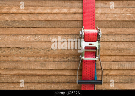 Sangle à cliquet rouge fixant les planches de bois / bois / tables empilées Banque D'Images