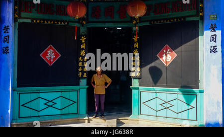 Homme debout à l'extérieur d'un temple chinois dans la vieille ville de Hoi An, Vietnam Banque D'Images