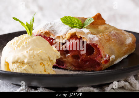 Des cherry strudel aux pommes avec du sucre en poudre et glace vanille close-up sur une plaque horizontale. Banque D'Images