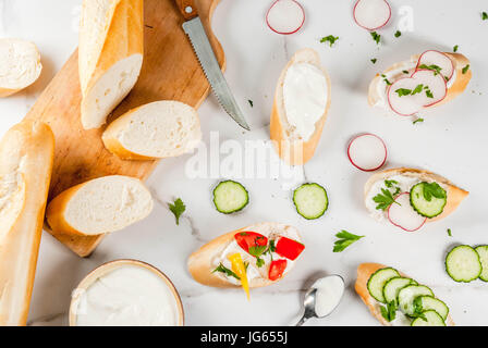 Alimentation saine. Le printemps, l'été des collations. Toast sandwiches avec du fromage à la crème et légumes frais - radis, concombres, tomates, oignon, poivre. Sur Banque D'Images