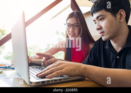 Jeune couple étudiant dans la salle de séjour avec cheminée de textes sur table. Banque D'Images