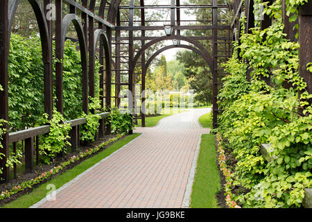 Alcôve dans le parkSurrounded par une belle bush, un gazebo en bois de haute qualité, une soignée pelouse et fleurs avec un chemin de pierre menant à la Banque D'Images