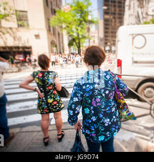 Les femmes portant des impressions florales attendre un feu de circulation pour changer sur la Cinquième Avenue à Manhattan, le vendredi, 30 juin 2017. Les tempêtes sont attendues le samedi en début de week-end du 4 juillet, mais les prochains jours après que devrait être bonne et ensoleillée, avec une faible humidité le 4 juillet. (© Richard B. Levine) Photo illustration Banque D'Images