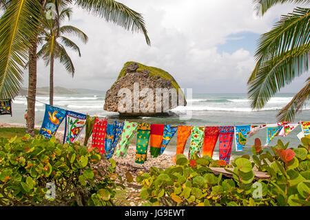 La Barbade Bethsabée boulder dramatique sur plage déserte avec des vêtements colorés sur corde qui souffle dans le vent. Banque D'Images