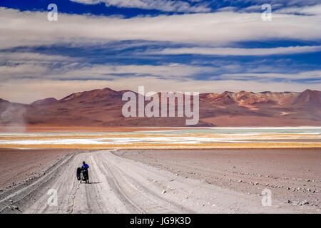 Cycliste femme aux prises et en poussant son vélo sur la route de sable en carton ondulé de l'Altiplano en Bolivie Banque D'Images