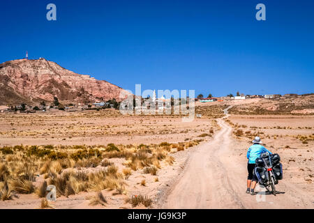 Femme poussant son vélo sur la route de sable dans la partie éloignée de la Bolivie, près de la petite ville dans les montagnes Banque D'Images