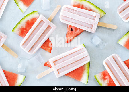 Le jus de melon d'eau naturelle les sucettes glacées avec des cubes de glace sur fond gris. Dessert d'été en bonne santé. Banque D'Images