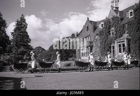 1940, en Angleterre, dans l'Essex, groupe d'infirmières et des poussettes à roues chromées dans les motifs de Stanstead Hall, maison de Sydney Courtauld, Lady Butler, avec jeunes enfants évacués de Wellgarth infant school, Hamptead Quartiers après qu'il a été détruit par une mine terrestre. Banque D'Images