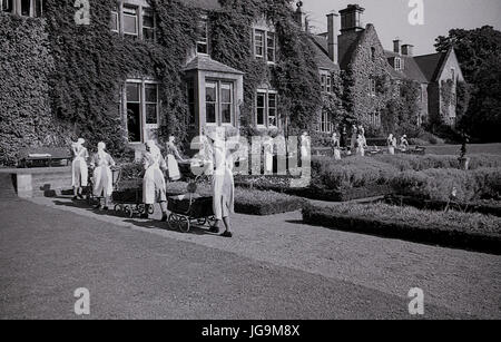 1940, en Angleterre, dans l'Essex, groupe d'infirmières et des poussettes à roues chromées dans les motifs de Stanstead Hall, maison de Sydney Courtauld, Lady Butler, avec jeunes enfants évacués de Wellgarth infant school, Hamptead Quartiers après qu'il a été détruit par une mine terrestre. Banque D'Images