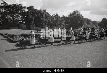 1940, en Angleterre, dans l'Essex, groupe d'infirmières et des poussettes à roues chromées dans les motifs de Stanstead Hall, maison de Sydney Courtauld, Lady Butler, avec jeunes enfants évacués de Wellgarth infant school, Hamptead Quartiers après qu'il a été détruit par une mine terrestre. Banque D'Images