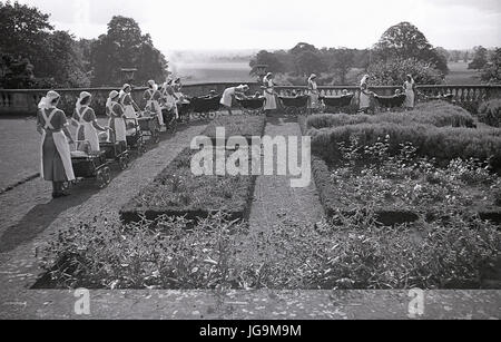 1940, en Angleterre, dans l'Essex, groupe d'infirmières et des poussettes à roues chromées dans les motifs de Stanstead Hall, maison de Sydney Courtauld, Lady Butler, avec jeunes enfants évacués de Wellgarth infant school, Hamptead Quartiers après qu'il a été détruit par une mine terrestre. Banque D'Images