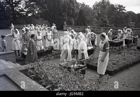 1940, en Angleterre, dans l'Essex, groupe d'infirmières et des poussettes à roues chromées dans les motifs de Stanstead Hall, maison de Sydney Courtauld, Lady Butler, avec jeunes enfants évacués de Wellgarth infant school, Hamptead Quartiers après qu'il a été détruit par une mine terrestre. Banque D'Images