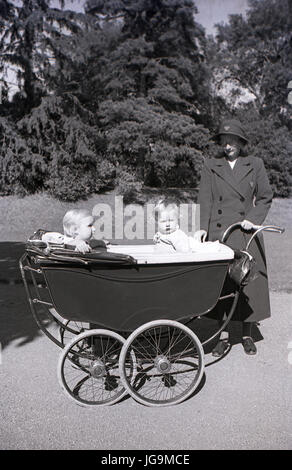 1940, en Angleterre, de guerre évacués, nounou avec de petits enfants assis à l'extérieur dans un autocar à roues chromées construit Pram, dans les motifs de Stanstead Hall, la maison de Sydney Courtauld, Lady Butler, épouse de Rab Butler, homme politique conservateur. Banque D'Images