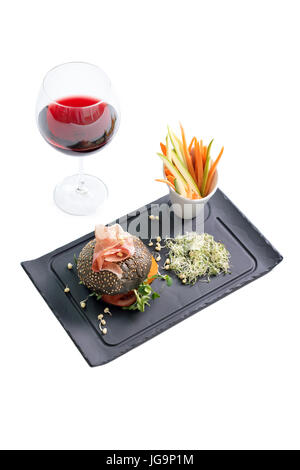 Burger sain avec hamon, tomates, pousses et noir, petits pains à grains entiers de bâtonnets de légumes et de vin rouge à l'ardoise noire sur fond blanc. Nettoyer, alimentaires, les régimes alimentaires detox concept. Banque D'Images