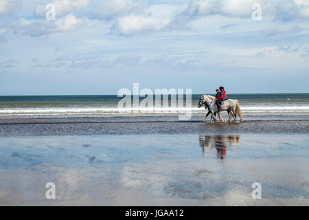 Trois femmes de l'équitation sur la plage et la mer Satburn dans Angleterre du Nord-Est, Royaume-Uni Banque D'Images