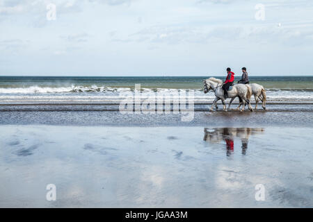 Trois femmes de l'équitation sur la plage et la mer Satburn dans Angleterre du Nord-Est, Royaume-Uni Banque D'Images