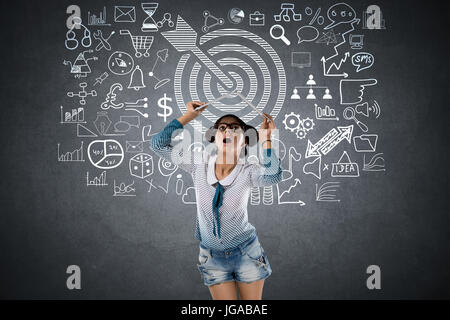 Choqué woman in front of blackboard avec dart cible et symbole Banque D'Images