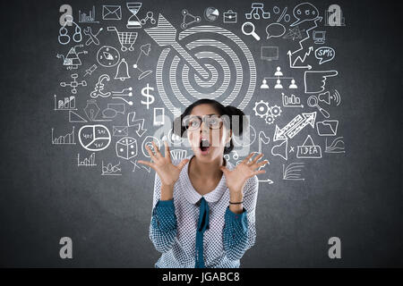 Choqué woman in front of blackboard avec dart cible et symbole Banque D'Images