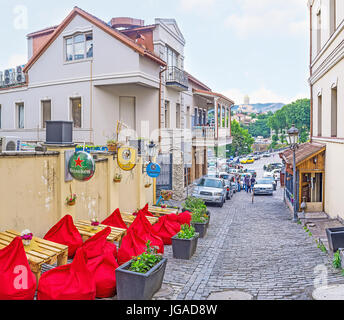 Tbilissi, Géorgie - juin 5, 2016 : l'agréable café en plein air avec des tables en bois et chaises de sac dans l'étroite rue vallonné dans quartier Abanotubani, sur Ju Banque D'Images