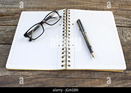 Stylo et carnet à spirales avec lunettes sur table en bois Banque D'Images