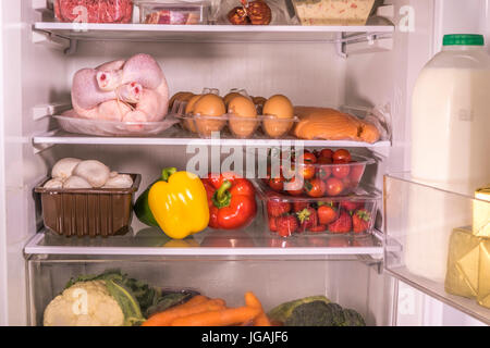 Un réfrigérateur avec divers éléments d'aliments frais et les boissons sur les étagères en verre. Angleterre, Royaume-Uni. Banque D'Images