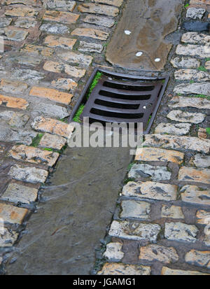 D'eaux pluviales dans une rue pavée, un jour de pluie Banque D'Images