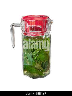 Vitamine detox de refroidissement fait à partir de feuilles de menthe broyées et de groseilles dans un grand pot en verre transparent avec couvercle rouge isolé sur fond blanc. Banque D'Images