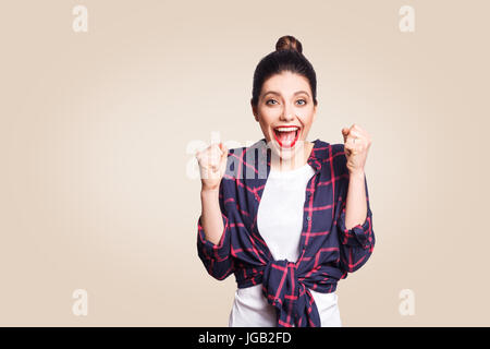 Surpris portrait d'heureux gagnant en extase jeune femme avec style casual ayant air choqué, s'exclamant, en gardant la bouche grande ouverte et les poings serrés Banque D'Images