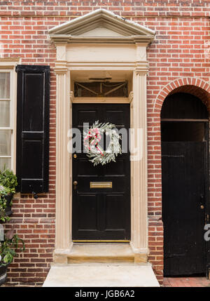 Porte rouge coloniale dans la ville historique De Elfreth's Alley à Philadelphie avec fronton et couronne de Noël Banque D'Images
