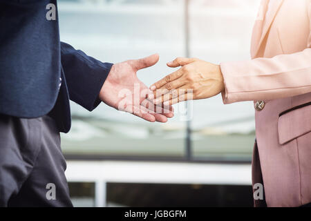 Libre réunion amicale poignée de main entre femme et homme d'affaires avec la lumière du soleil. Banque D'Images