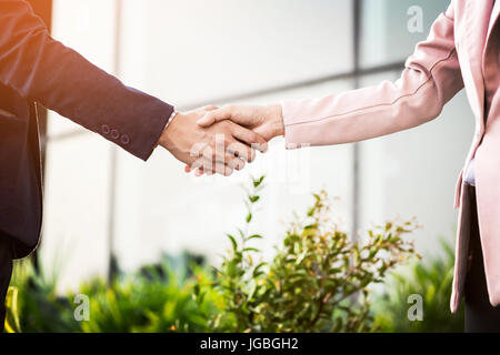Libre réunion amicale poignée de main entre femme et homme d'affaires avec la lumière du soleil. Banque D'Images