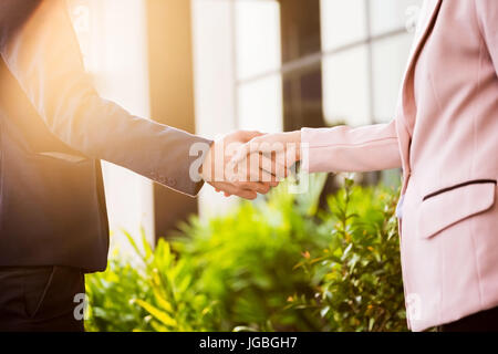 Libre réunion amicale poignée de main entre femme et homme d'affaires avec la lumière du soleil. Banque D'Images
