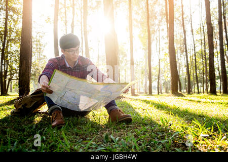 Meilleur homme hiker marcher sous les rayons du soleil dans la forêt de montagne et regarder la carte. Banque D'Images