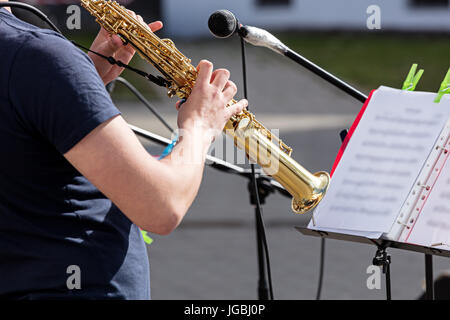 Mains de musicien masculin à jouer du saxophone sur fond de rue ville floue Banque D'Images