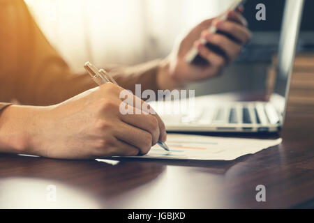 L'homme d'affaires part écrit et holding phone in office. Banque D'Images