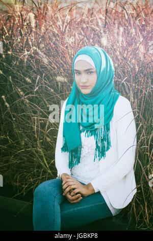 Jeune femme musulmane sérieuse portant hijab sitting outdoors Banque D'Images