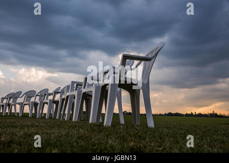 Des chaises en plastique blanc sur une prairie disposées en cercle pour la méditation. Banque D'Images